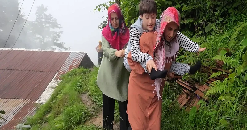 Yağmur çamur demeden Down sendromlu kızı Zümra’yı sırtında taşıyan anne, bölgeye yol yapılmasını istiyor