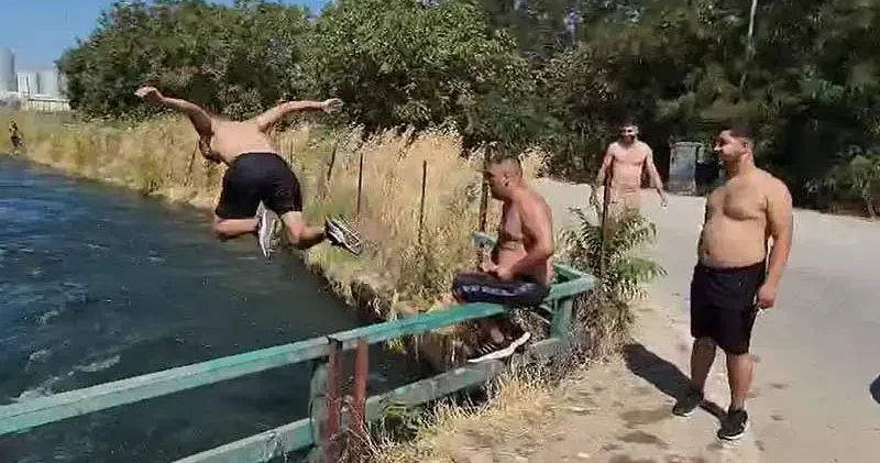 Tehlikeye aldırmadan sulama kanalında serinlediler