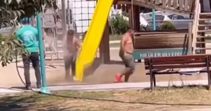 Temizlik personeli, parktaki çocukları hortumla su sıkarak serinletti