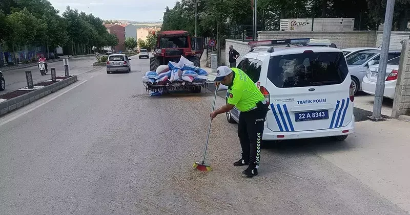 Polis, traktörden düşerek yola saçılan kuzu yemlerini topladı
