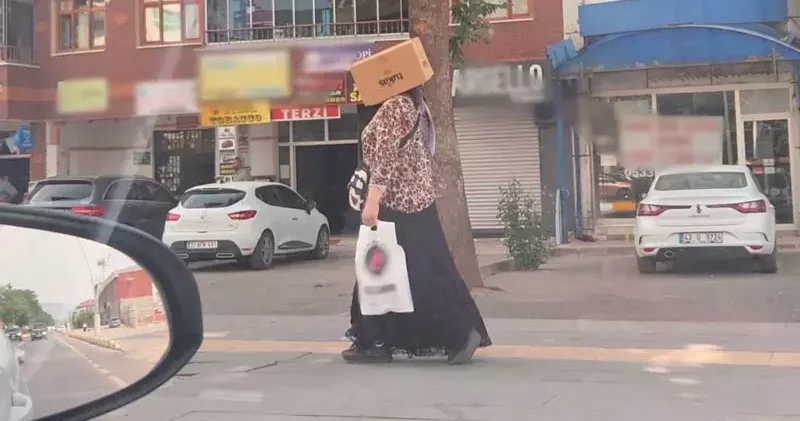Başına karton kutu geçirerek sıcaktan korunmaya çalıştı