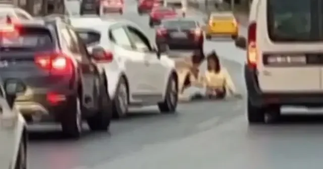 İstanbul da araçların geçtiği esnada yola atlayıp oturan kadın trafiği felç etti VİDEO İZLE