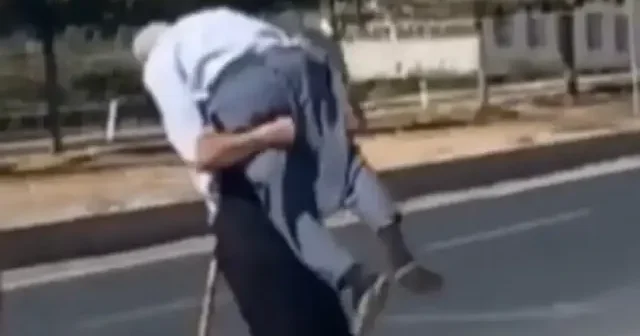 Güvenlik görevlisi yaşlı adamı karşıya geçmesi için sırtında taşıdı VİDEO İZLE