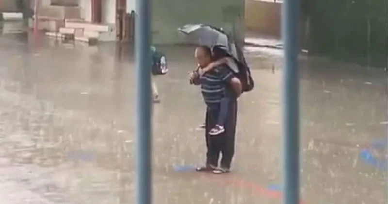 Dede yağmur altında torununu sırtına alıp İstiklal Marşı okudu
